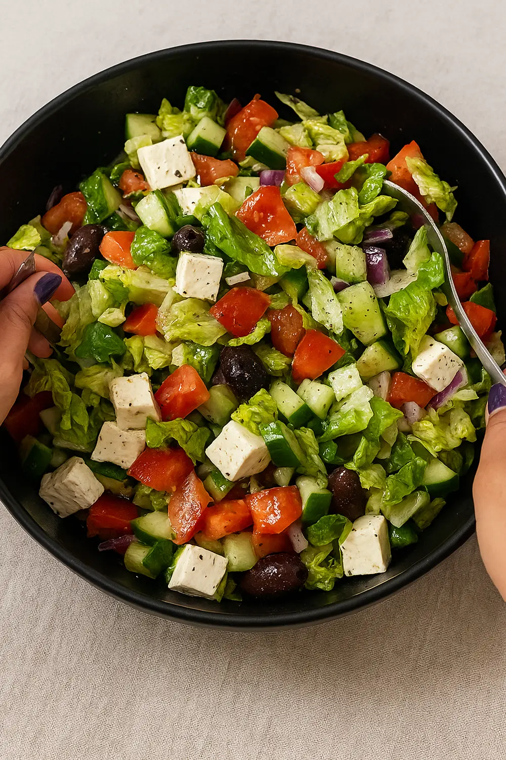 Mediterranean Greek Salad Recipe Greek tomato cucumber salad featuring fresh cucumbers, ripe tomatoes, feta cheese cubes, black olives, and romaine lettuce in a black serving bowl