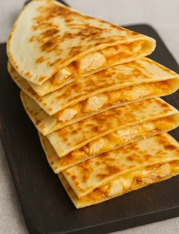 Taco Bell Chicken Quesadilla Recipe with Jalapeño Sauce Homemade Taco Bell chicken quesadilla recipe with melted cheese and grilled tortillas served on a wooden board